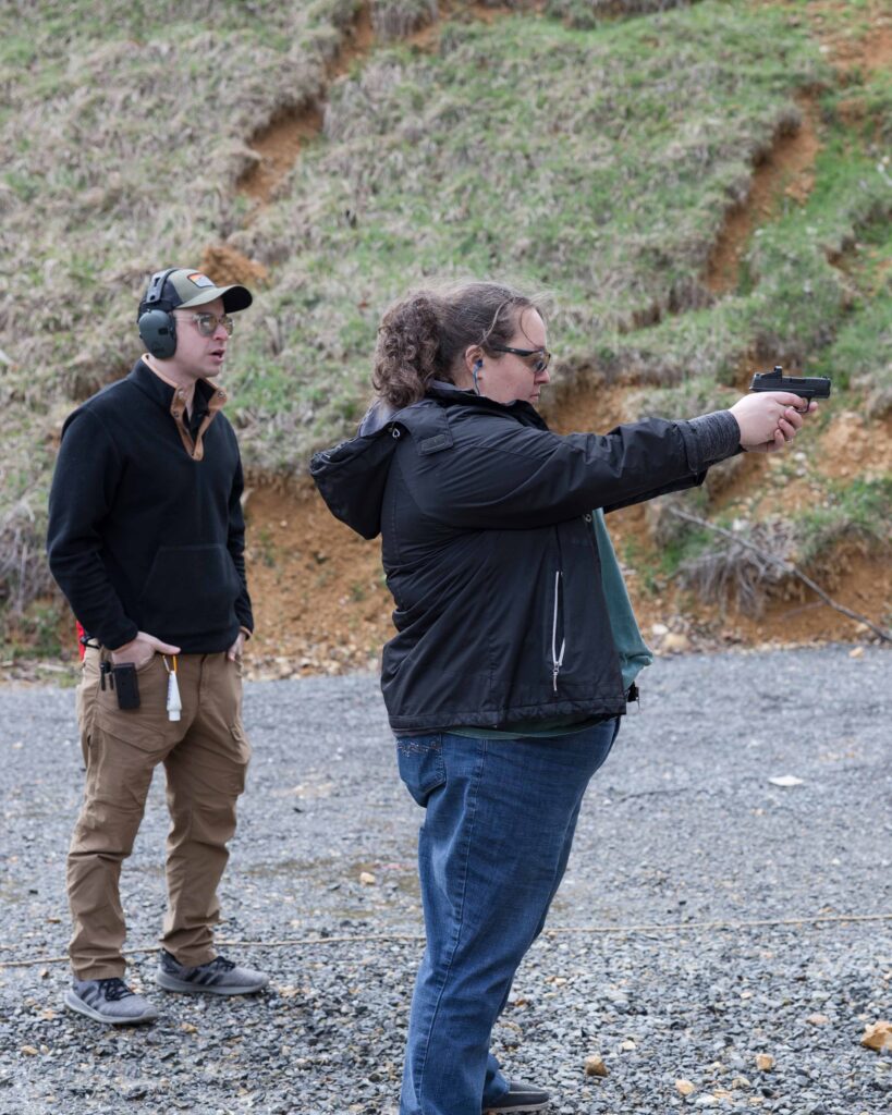 Participant receiving focused attention and mentorship from a skilled instructor during a private gun safety class held outdoors.